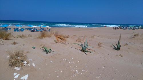 a sandy beach with people sitting on the beach at 360 Panorama House - Gazing at Horizon and the Stars of the Galaxy in the night - Fresh Cool breeze most of the time - just 7 min from the beach in Kournás
