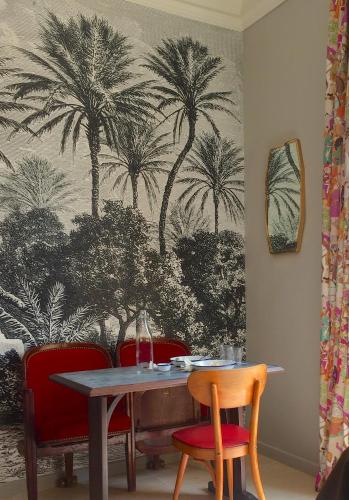 une table et des chaises avec des palmiers sur un mur dans l'établissement Maison Du Collectionneur, à Aix-en-Provence