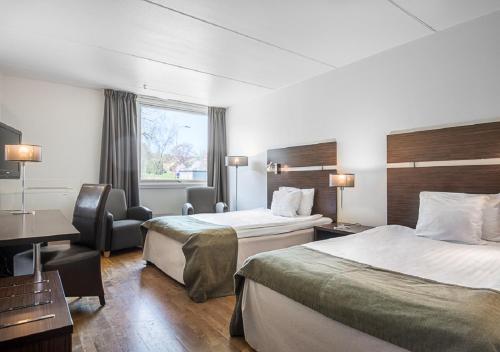 a hotel room with two beds and a desk at Quality Hotel Winn in Gothenburg