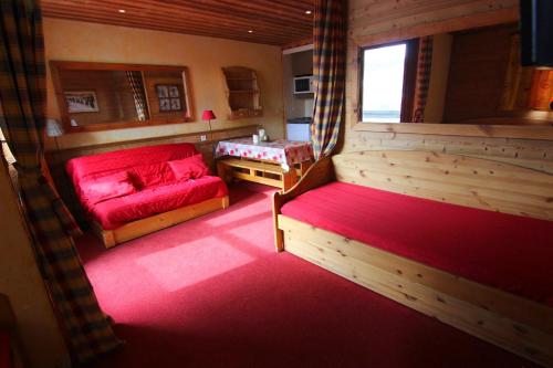 Cette petite chambre comprend un canapé rouge et une table. dans l'établissement Lauzieres Appartements VTI, à Val Thorens