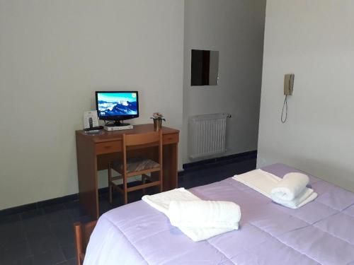 Schlafzimmer mit einem Bett und einem Schreibtisch mit einem TV in der Unterkunft Pensione Nettuno in Palinuro
