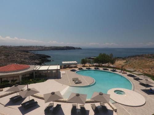 an overhead view of a pool with umbrellas and the ocean at Kavos Hotel & Suites in Stavros