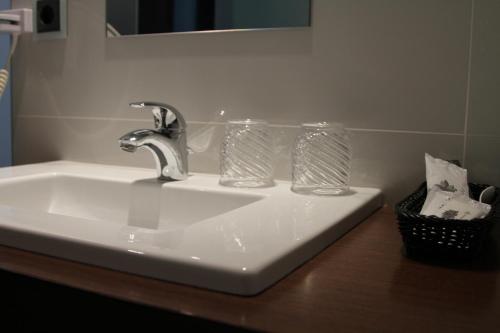 a bathroom sink with two glasses on a counter at Lazza Hotel in Figueira da Foz