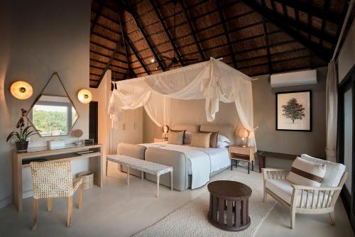 um quarto com uma cama, uma secretária e uma cadeira. em Lion Sands River Lodge em Sabi Sand Game Reserve