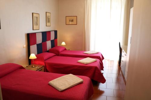 una camera d'albergo con tre letti con lenzuola rosse di L'elefante a Catania