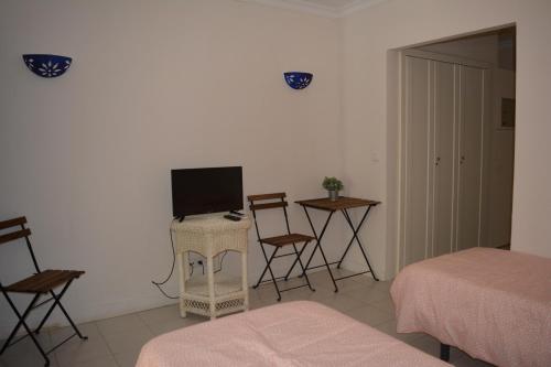 uma sala de estar com televisão e uma cama e cadeiras em Estudio Piscina e Praia, Cabanas de Tavira em Tavira