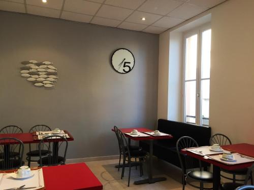 uma sala de jantar com mesas e um relógio na parede em Hôtel du Commerce em Les Sables-dʼOlonne