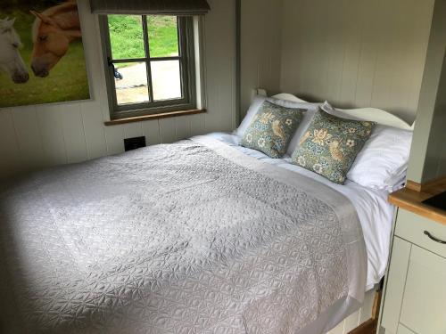 a bedroom with a white bed with pillows and a window at Luxury Shepherds Hut in Bransgore