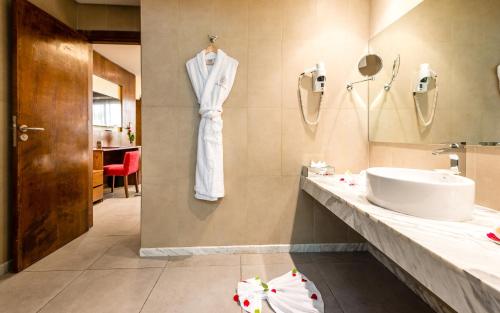 a bathroom with a white robe hanging on a wall at Sahara Hotel Agadir - Adults Only in Agadir