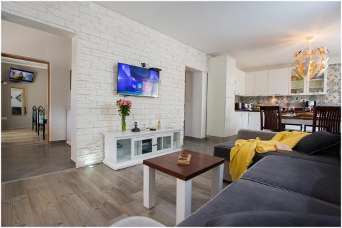a living room with a couch and a tv on a brick wall at House Mellifera in Razvođe