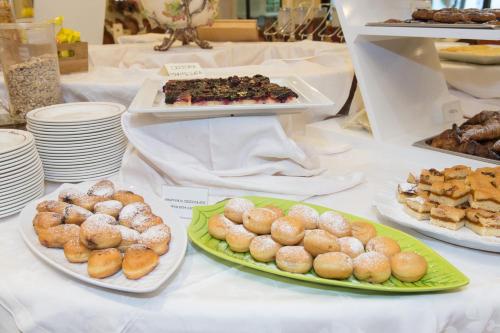 a table topped with plates of donuts and other pastries at Grand Hotel Liberty in Riva del Garda