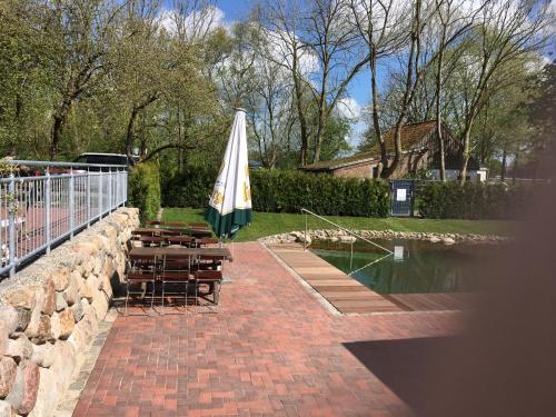 a patio with benches and an umbrella next to a pond at Gasthof Oldenwöhrden in Wöhrden