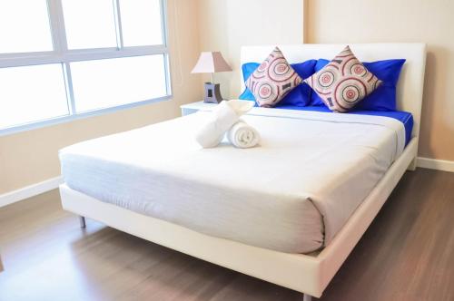 a large white bed with blue and red pillows at Baan Thew Lom @ Sea in Cha Am