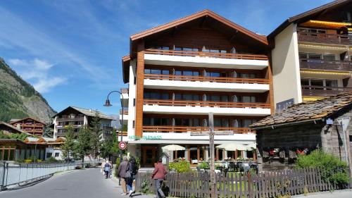 a large building with people walking down a street at Hotel Parnass in Zermatt