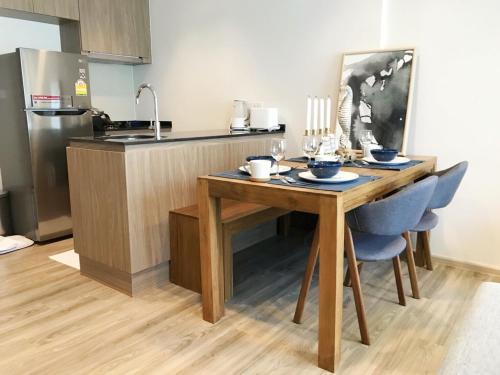 a kitchen with a wooden table with blue chairs at Rain Cha-am Huahin By Sake in Cha Am