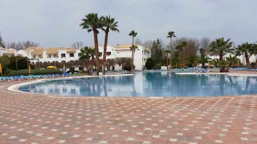 uma grande piscina com cadeiras e palmeiras em Estudio Piscina e Praia, Cabanas de Tavira em Tavira