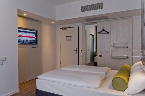 a bedroom with a large white bed with yellow pillows at Super 8 by Wyndham Munich City West in Munich