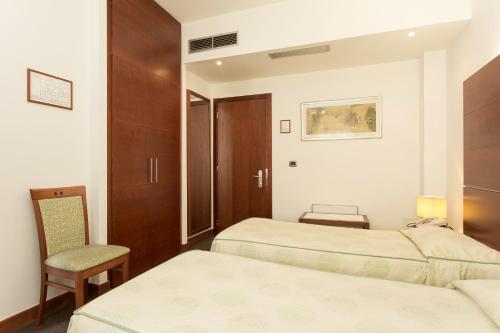 a hotel room with two beds and a chair at Millennhotel in Bologna
