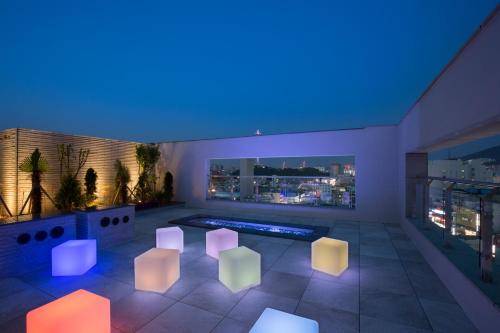 a rooftop patio with white chairs and a pool at Nampo Hound Hotel Premier in Busan