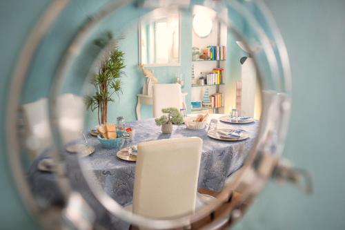 マリーナ・ディ・カッラーラにあるBed & Breakfast Veneziaのダイニングルームテーブル(青いテーブルクロス、白い椅子付)
