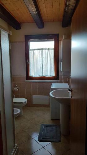 a bathroom with a sink and a toilet and a window at Corallo casa vacanza in Villaputzu