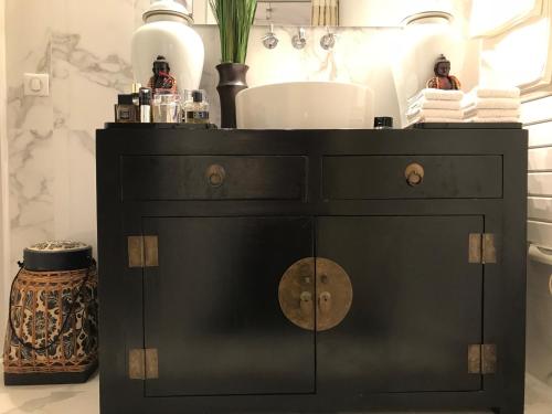 - une armoire noire avec lavabo dans la salle de bains dans l'établissement Le Marais Maison En Ville, à Paris