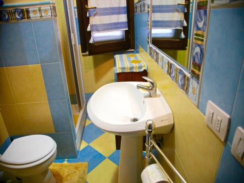 ein Badezimmer mit einem weißen Waschbecken und einem WC in der Unterkunft Ischia Apartment in Campofelice di Roccella
