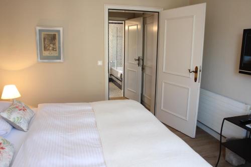 a bedroom with a white bed and an open door at The Little Guesthouse in Salzburg