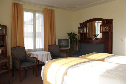a hotel room with a bed and chairs and a tv at Gasthaus zum Kreuz in Luzern