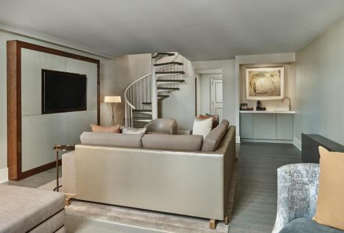 a living room with a couch and a staircase at Hotel Crescent Court in Dallas