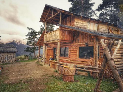 a log cabin with a tree stump in front of it at Heshkili huts and cabins Svaneti in Keshkili