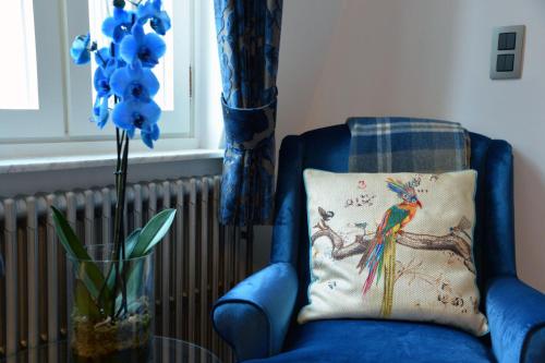 a blue chair with a pillow and a vase with a peacock at Notarishuis Beveren B&B in Beveren