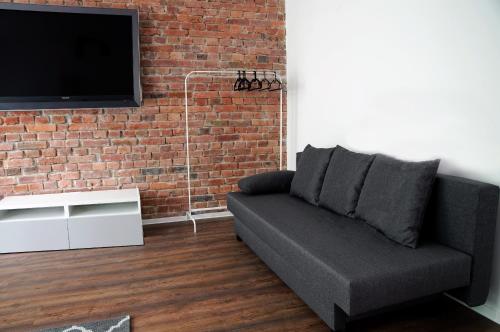 ein Wohnzimmer mit Sofa und Ziegelwand in der Unterkunft Kamienica Wygon Apartment in Danzig