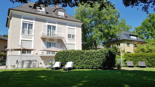 a large white building with chairs in front of it at The Little Guesthouse in Salzburg
