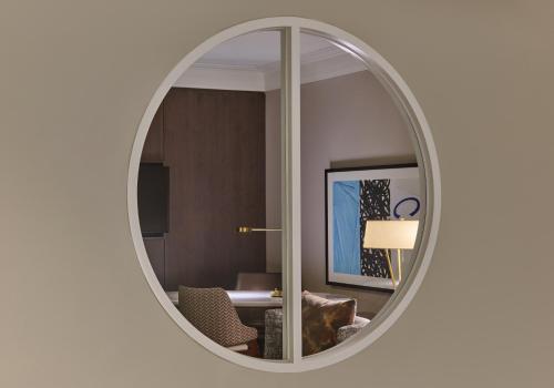 a round mirror on a white wall in a room at Hotel Crescent Court in Dallas