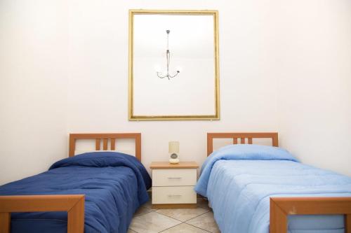 a bedroom with two beds and a mirror on the wall at By the Sea in Terrasini