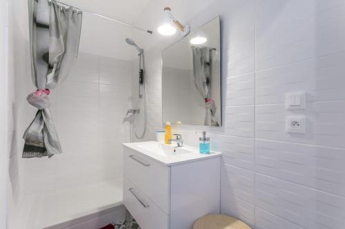 a white bathroom with a sink and a shower at Sunny Relaxing Apartement in Béziers