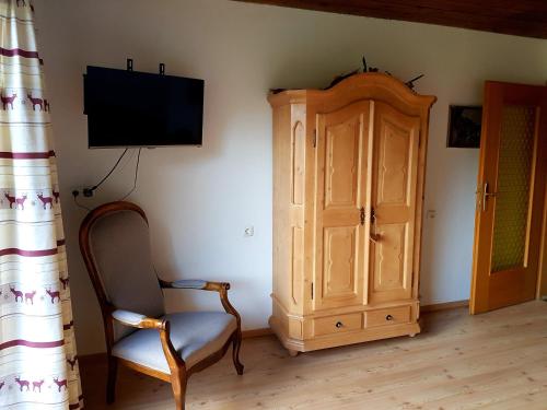 a room with a tv and a chair and a cabinet at Tyrol Appartements in Ehrwald