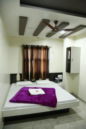a bedroom with a bed with a purple blanket on it at Hotel Arzoo Palace in Ajmer