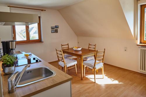 フリードリヒスハーフェンにあるBodenSEE Apartment Friedrichshafen SEENAHのキッチン(シンク、テーブル、椅子付)