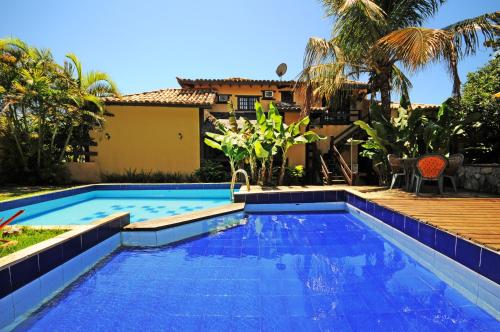 a swimming pool with a house in the background at Estrelamar Ferradura Pousada Restaurante & Spa in Búzios