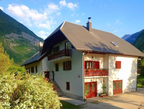 Cette maison blanche dispose de portes rouges et d'un balcon. dans l'établissement Apartment Joži, à Vallée de la Soča