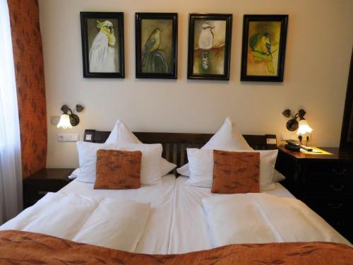 a bedroom with a white bed with four pictures on the wall at Aparthotel Guzulka & Restaurant in Berlin