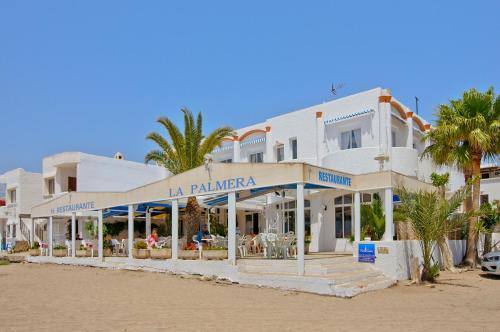 un hotel en la playa con palmeras delante en La Palmera. El amanecer en el Parque Natural en Agua Amarga