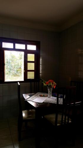 una mesa de comedor con un jarrón de flores. en Apartamento Vista Linda en Santa Teresa