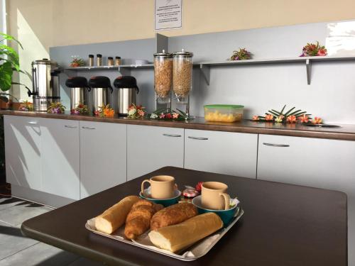 a table with a tray of loaves of bread and cups at Tahiti Airport Motel in Faaa