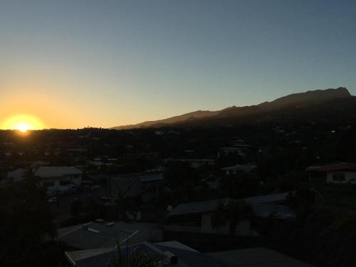a sunset over a city with mountains in the background at Tahiti Airport Motel in Faaa