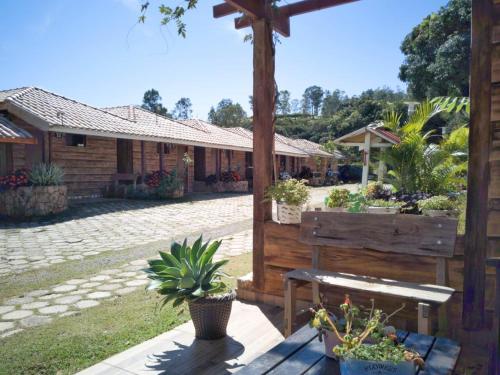 a wooden bench in front of a house with potted plants at Fazenda Morro Pelado in Águas de Lindóia