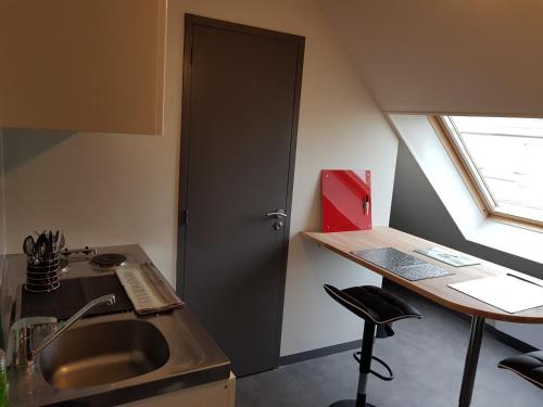 eine Küche mit einem Waschbecken und einem Schreibtisch mit einem Fenster in der Unterkunft Appartement Hyper centre - Quartier du château de Vire in Vire