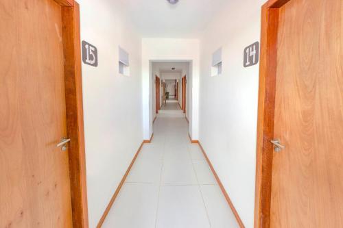 a hallway with white walls and white floors and doors at Economy Apart in Natal